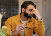 Man in a yellow jacket holding glasses with a blurred background